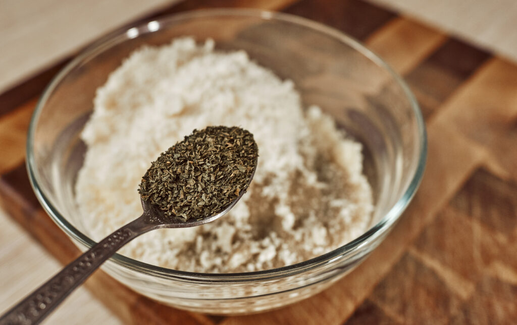 Adding dried basil to Parmesan breadcrumb mixture