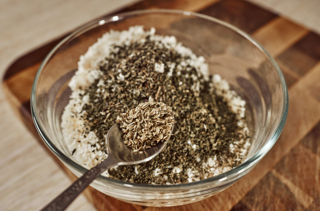 Sprinkling dried oregano over Parmesan breadcrumbs