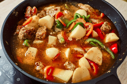 Adding potatoes to the pork stew