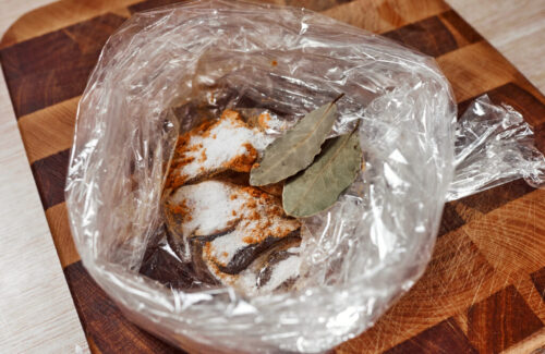 adding bay leaves to seasoning mixture in bag