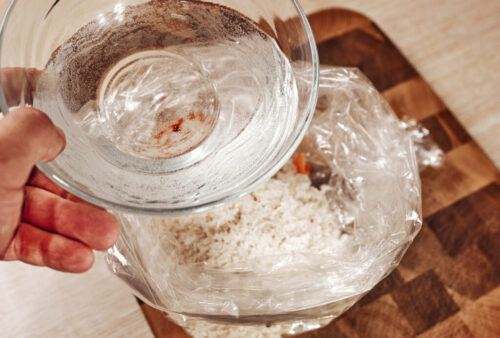 pouring water or chicken stock over rice and vegetables in baking bag