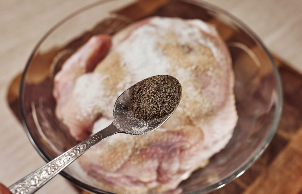 adding ground black pepper to chicken