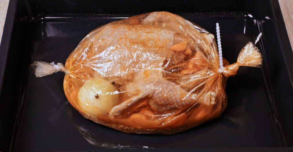 whole chicken with rice and vegetables sealed in a baking bag ready for the oven