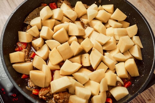 Adding potatoes, garlic, and bay leaves