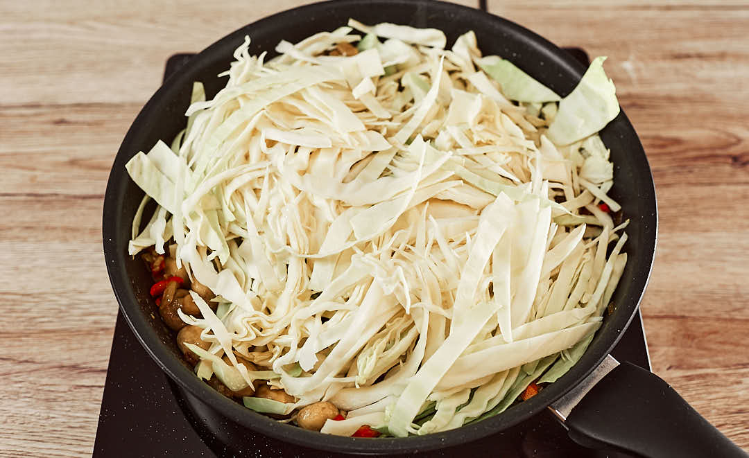 Adding shredded cabbage to the pan
