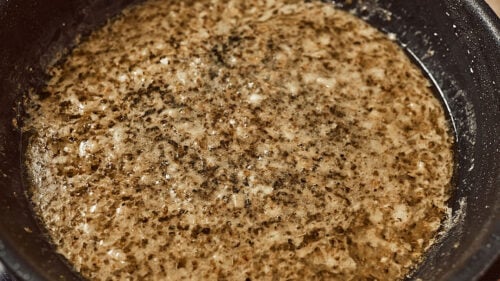 Cooking garlic butter sauce in skillet with oregano