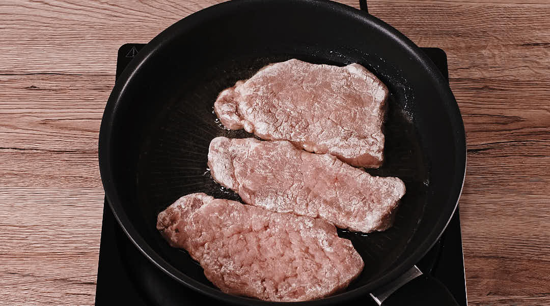 Pork schnitzel frying in pan