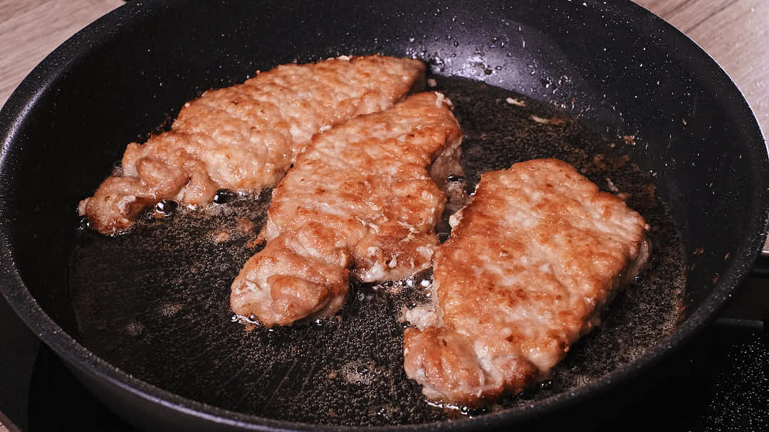 Golden brown pork schnitzel frying in pan