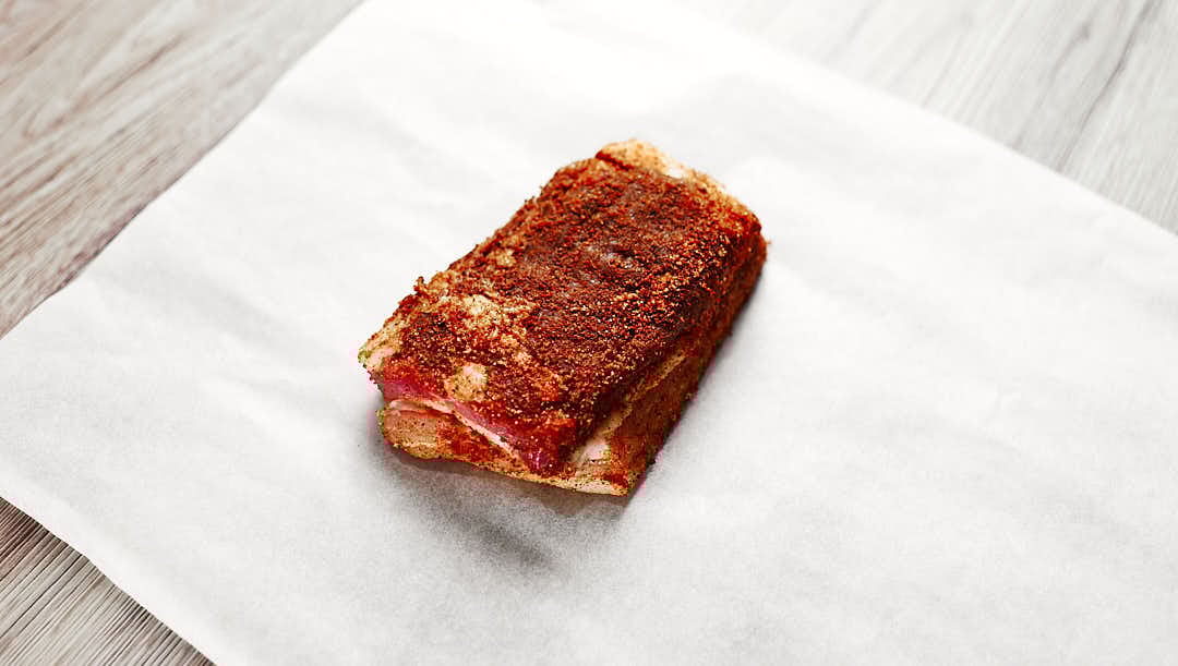 pork belly wrapped in parchment with peppercorns and bay leaf