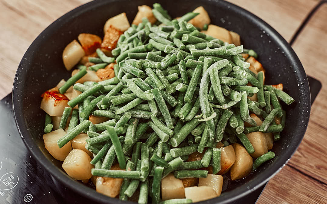 Cooking green beans with potatoes in olive oil