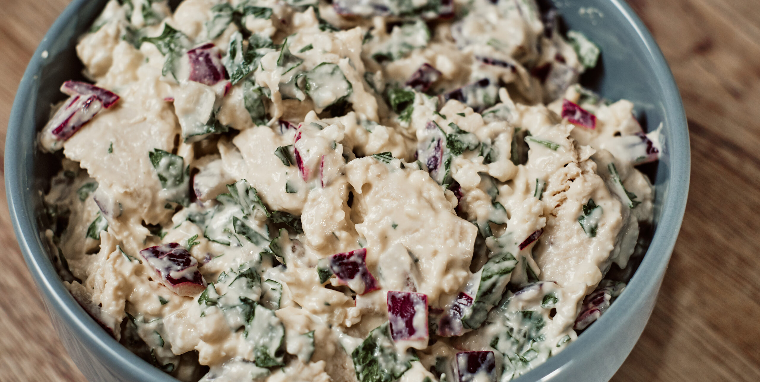 Tossing keto chicken salad with creamy dressing