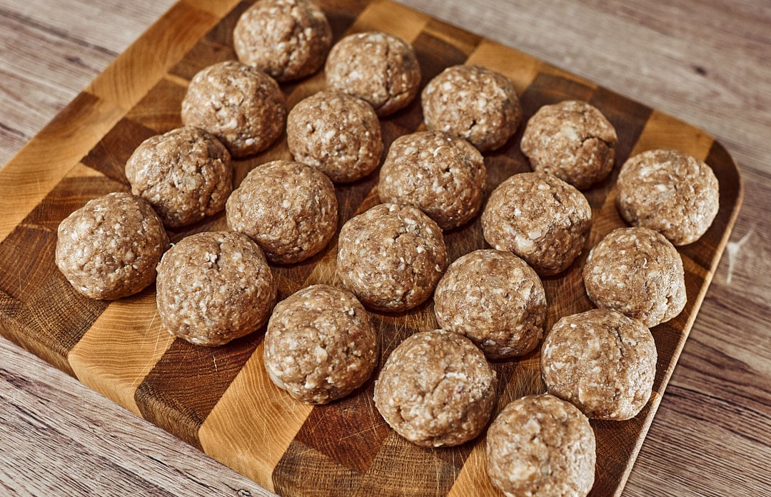 Rolling pork and beef meatballs on a board