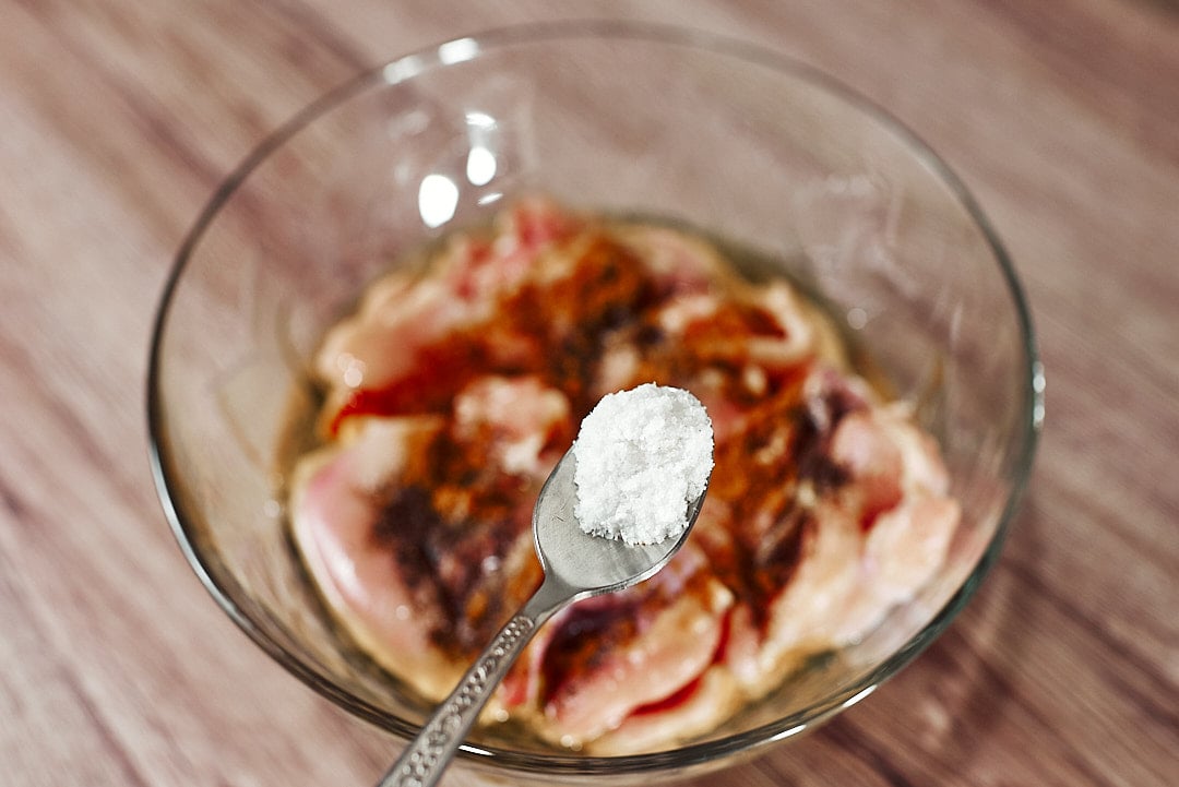 Seasoning chicken thighs with salt, paprika, coriander and chili