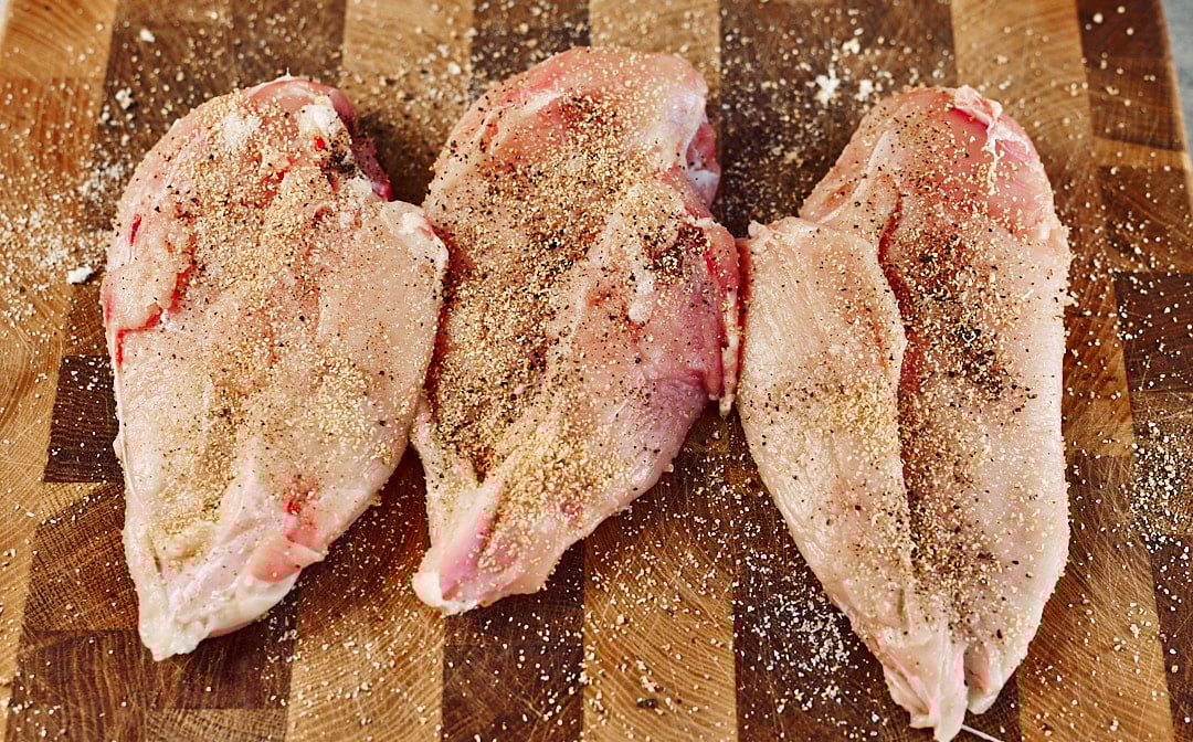 Seasoning chicken breasts with garlic and pepper