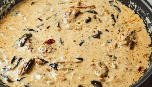 Stirring in cream, herbs, and sun-dried tomatoes