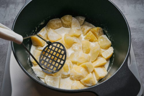 Starting to mash cooked potatoes