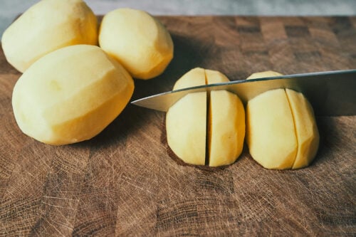 Slicing peeled potatoes into large chunks