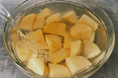 Potato chunks rinsing in a bowl of water