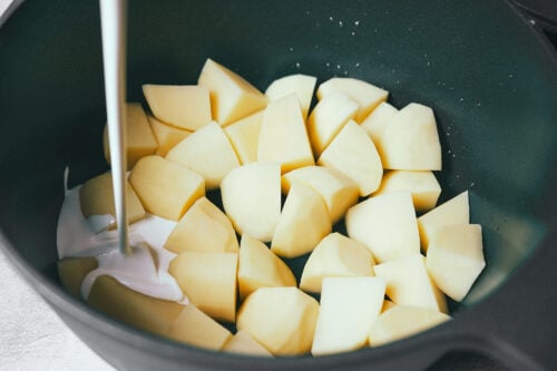 Heavy cream being poured over potatoes