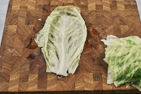 Soft cabbage leaf laid out on a cutting board before stuffing.