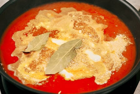 Bay leaves added to simmering cabbage roll sauce.