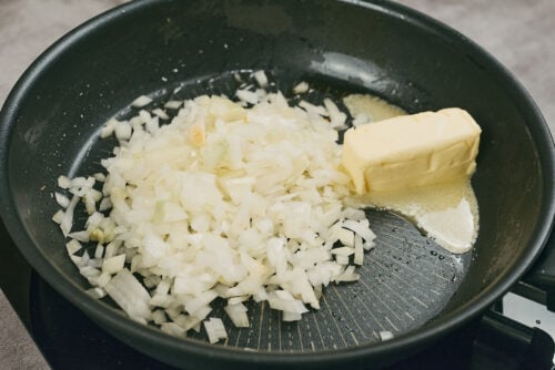 Chopped onion sautéing in butter for creamy chicken meatballs sauce