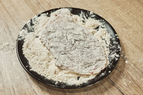 Pork cutlet dredged in flour as first step of breading