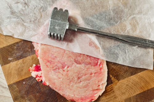 Pounding pork chop thin with a meat mallet
