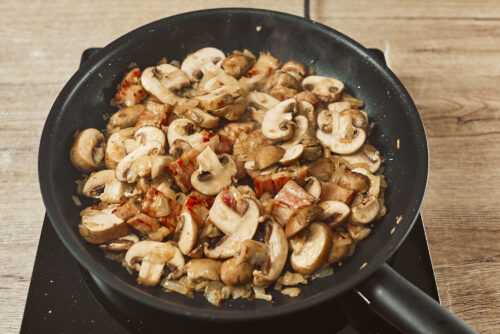 Sliced mushrooms added to skillet with bacon and onions