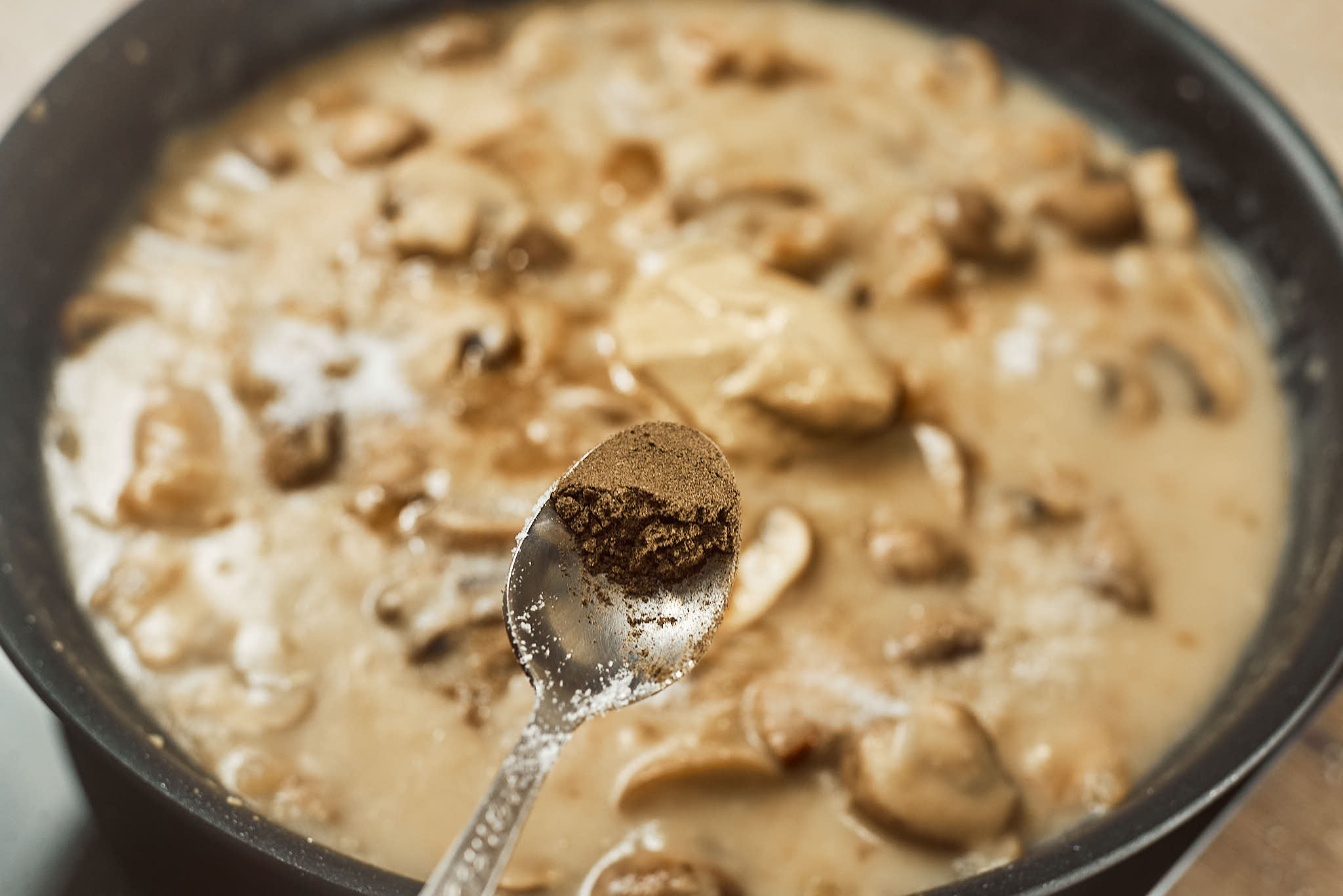 Black pepper added to creamy mushroom sauce