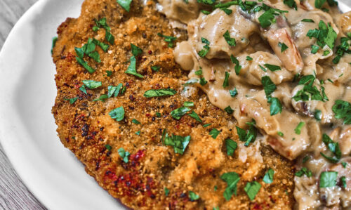 Crispy pork schnitzel topped with creamy mushroom gravy and fresh parsley