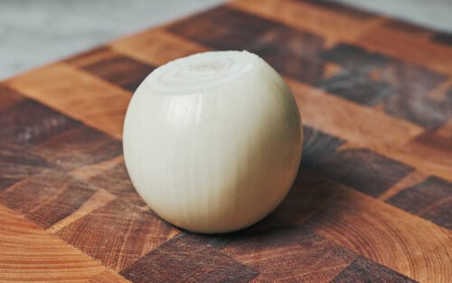 Whole onion on a cutting board for beef stroganoff