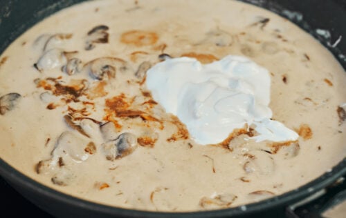 Stirring sour cream into beef stroganoff sauce