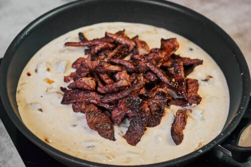 Adding seared beef back into creamy mushroom sauce for beef stroganoff