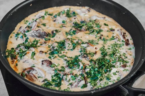 Stirring fresh parsley into beef stroganoff