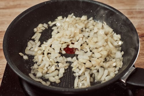 Chopped onions sautéing in a skillet until soft and translucent.