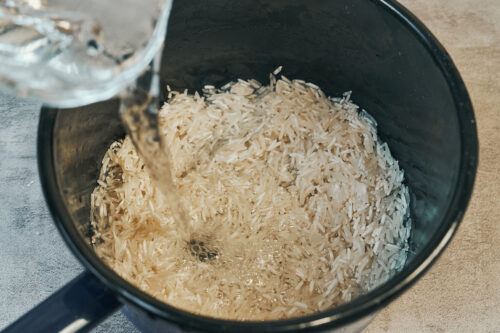 Adding water to rice in a saucepan