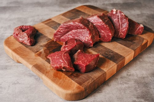 Beef chuck cut into large chunks on a cutting board