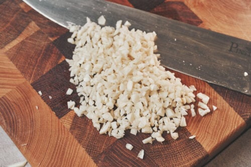 Finely chopped garlic on a wooden cutting board