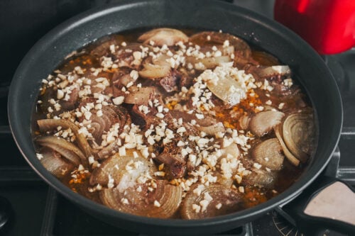 Garlic butter beef simmering with onions and chopped garlic