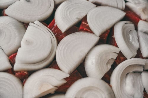 Onions covering beef to create the base of garlic butter sauce