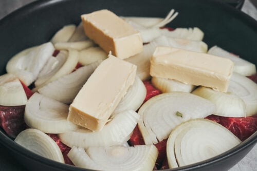 Unsalted butter added on top of onions for slow simmering