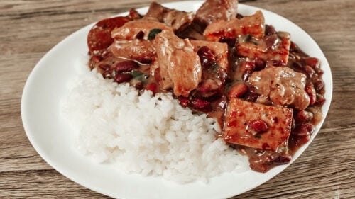 Creamy smoked sausage and pork bean stew plated with white rice for serving.