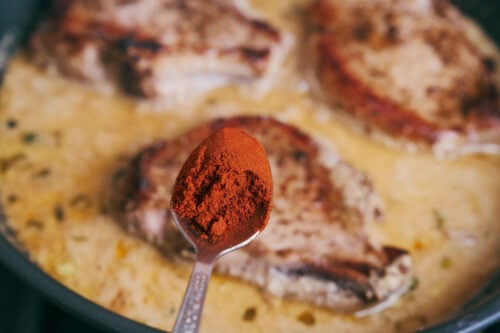 Paprika added to pork chops in sour cream sauce