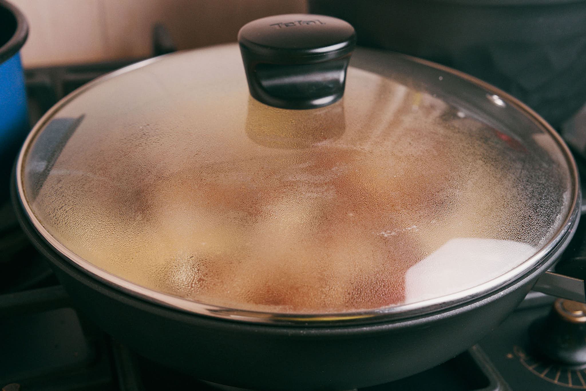 Pork chops simmering in sour cream sauce covered with a lid