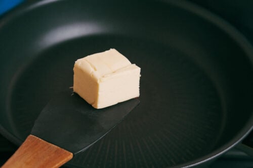 Butter being added to a skillet for searing pork chops