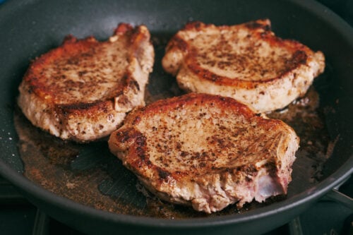 Pork chops seared until golden brown in a skillet