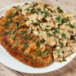 Crispy golden pork schnitzel topped with creamy mushroom sauce