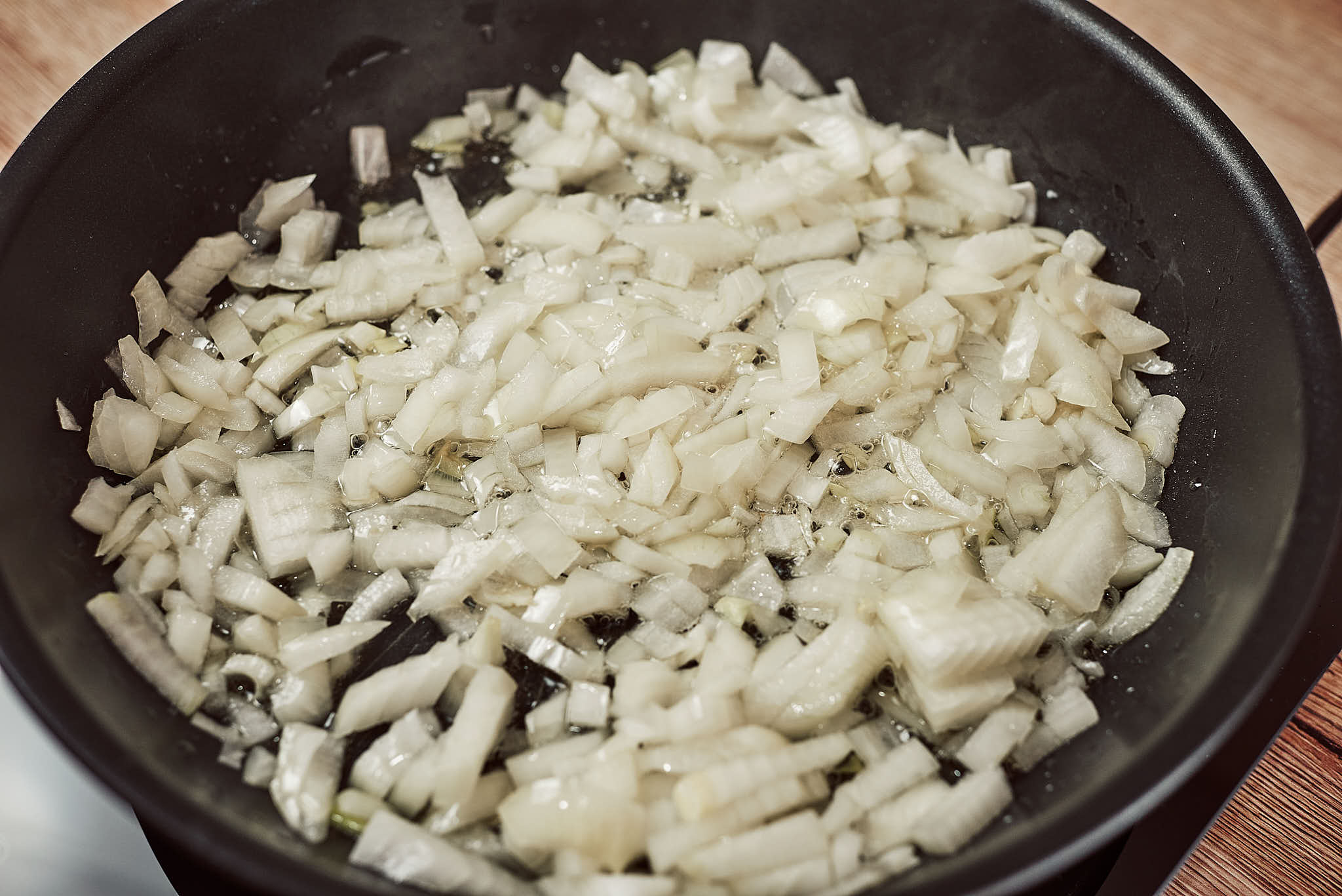Chopped onion sautéing in a pan until soft and translucent