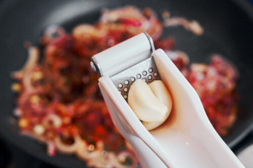 Garlic cloves being pressed for the creamy sauce